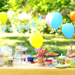 1st birthday party table decorated with sweet birthday treats, balloons, and gifts