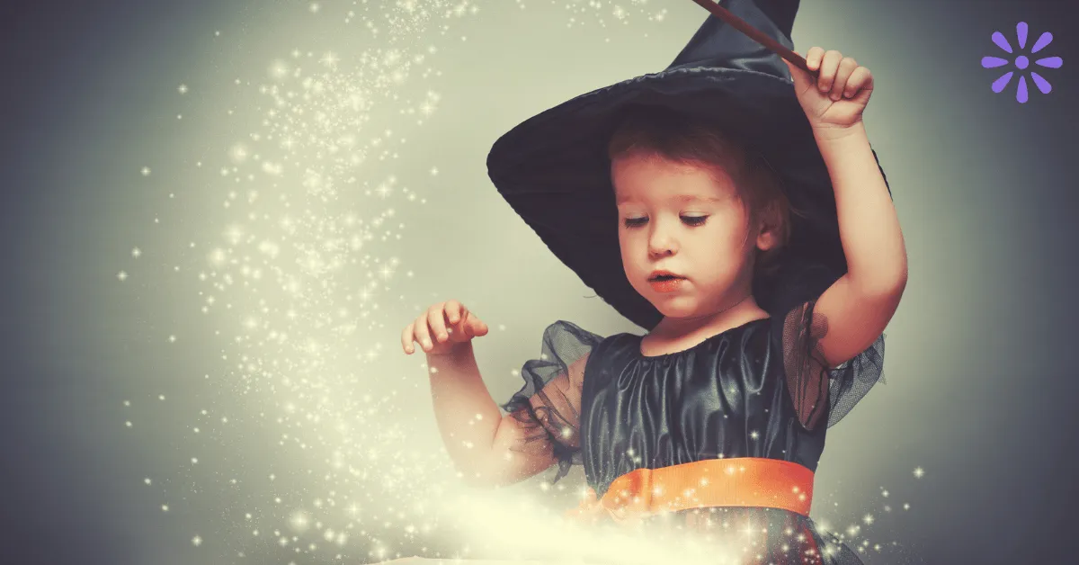 young girl in a witches costume waving a wand