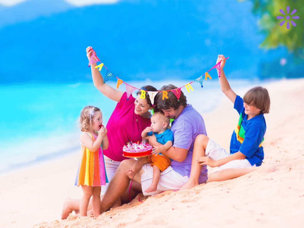 family with a baby, toddler, and young child celebrating a birthday at the beach
