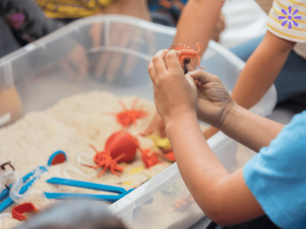 child playing with toys in a sensory bin filled with sand