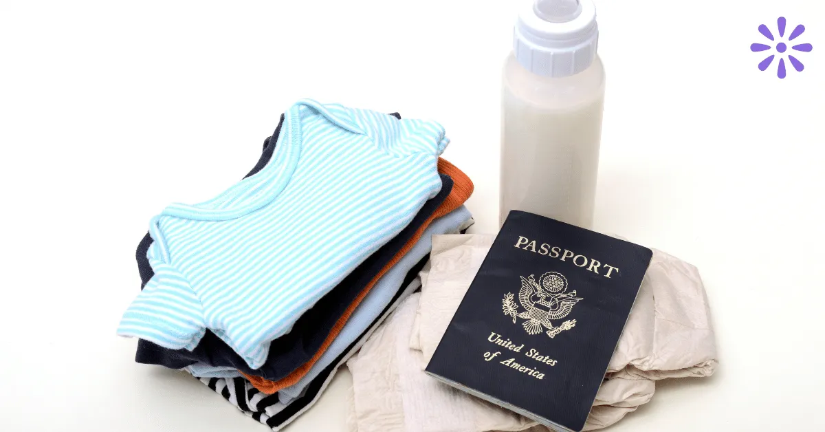 Infant passport on a white background with folded baby clothes and baby bottle