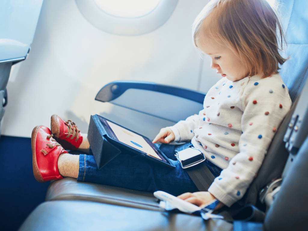 toddler entertaining herself on an airplane with a dvd player